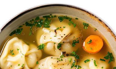Eine Schüssel Suppe mit Teigtaschen-Einlage, Karotten und Schnittlauch