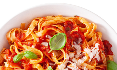 Nudeln mit Tomatensoße, bestreut mit etwas Parmesan und dekoriert mit Basilikum