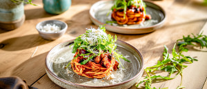 Spaghetti-Nester mit Speck, Auberginen und Rucola